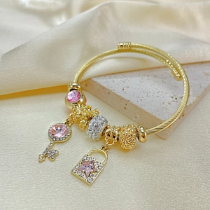 Gold beaded charm bracelet with pink crystal key and star lock pendant on silk