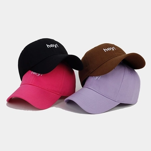 Close-up of four baseball caps with hey! embroidery in black brown pink and purple
