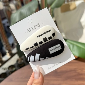 Detail of black and white fabric hair clips with Waterfall Sings text on packaging