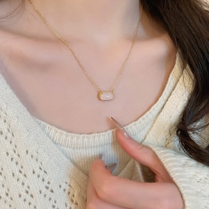 Gros plan d'un collier plaqué or 18k avec pendentif carré en résine rose sur un mannequin