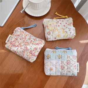 Detailed macro of three floral quilted cotton pouches with zip closure on a wooden table