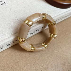 Macro shot of vintage resin marble blocks and golden metal beads on a stylish elastic bracelet