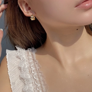 Close-up of a model wearing a thick polished gold geometric hoop earring for women