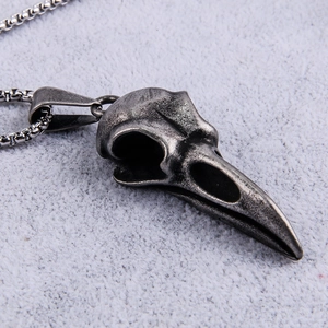 Close-up of vintage silver raven skull pendant with realistic bone texture on white fabric
