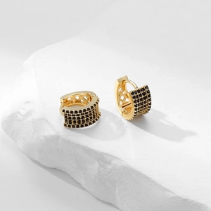 Macro shot of gold huggie earrings with pave black cubic zirconia on a stone base