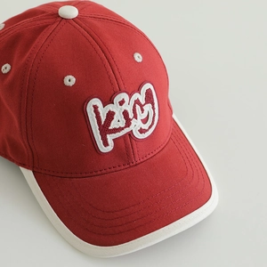 Red and beige kids baseball cap with kiy embroidery shown at a 45-degree angle