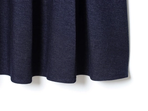 Dettaglio dell'orlo della gonna a pieghe blu scuro che mostra la trama del twill