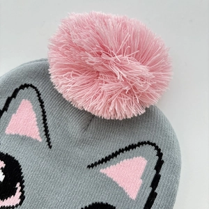 Close-up of a pink pom-pom on a gray knitted cat beanie for girls with soft textures