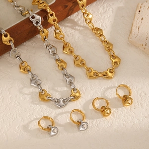Artistic layout of 18k gold plated heart necklace and hoop earrings on stone surface