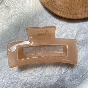 Macro shot of large pink rectangular hair claw clip with golden metal spring detail