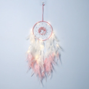 Macro detail of handmade dreamcatcher feathers and LED lights on a pink frame