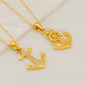 Detailed view of polished gold anchor and rudder pendants with sparkling zircon stones