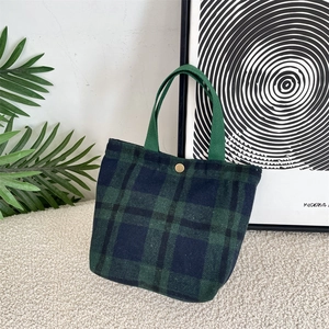 Dettaglio della borsa in lana a quadri retrò con manici verde scuro e chiusura magnetica dorata