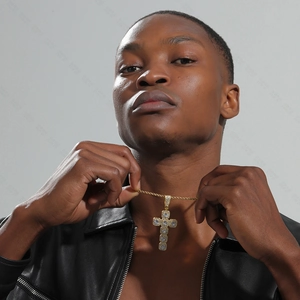 Close-up of a gold cross pendant necklace with clear zircons on a male model wearing black