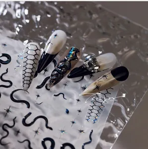 Detail of dark punk nail stickers with 3D gold snakes, holographic patterns, and star motifs