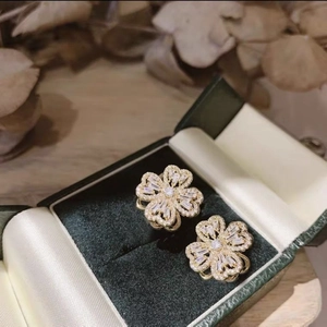 Elegant rotating clover earrings in gold finish with sparkling zircons on velvet box