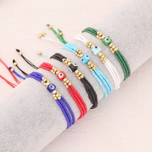 Bohemian woven seed bead bracelets with evil eye charms on a cylindrical display