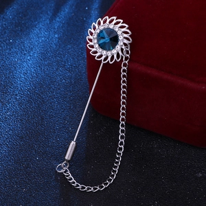 Detailed macro of a silver sunflower brooch pin with blue crystal and hanging metal chain