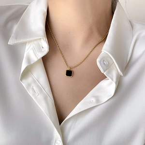 Detailed view of vintage gold twisted rope chain with black square onyx pendant on neck