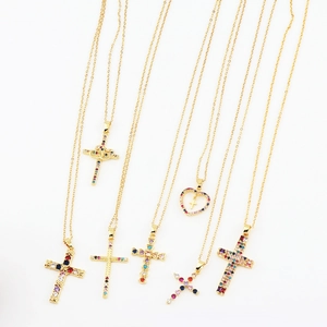 Close-up of gold cross and heart pendants with colorful zirconia on fine chains