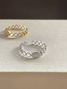 Detail of adjustable fish ring with cubic zirconia inlay in silver and gold finishes