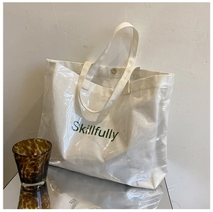 Close-up of large transparent PVC jelly tote bag with canvas interior and green text
