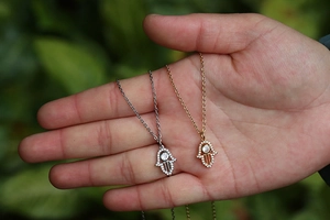Detailed view of gold and silver Hamsa hand pendants with micro-pave cubic zirconia stones