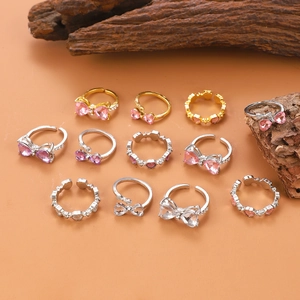 Elegante rosa Herz- und Bogen-Ringe in Gold und Silber auf einem Holzständer