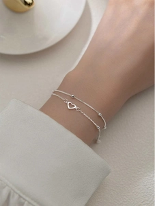 Close-up of double-layered silver heart bracelet with delicate beads worn on wrist