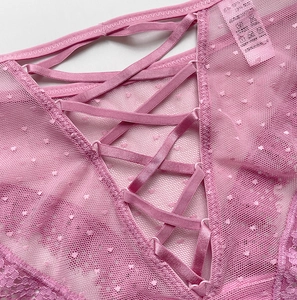Détail de culotte en dentelle rose avec lanières croisées et tulle à pois fin