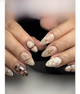 Detail of almond nails with 3D floral accents, leopard print and gold beads