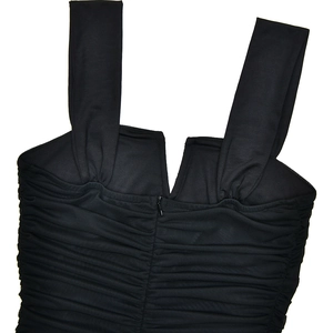 Close-up of the black dress featuring pleated chest details and a hidden center zipper