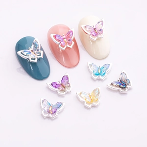 Close-up of butterfly nail charms with colorful crystals and silver metal frames