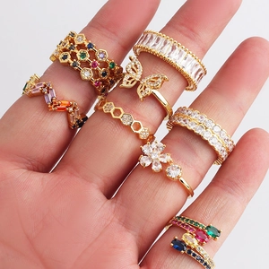 Close-up of golden rings with colorful crystals and butterfly design on hand