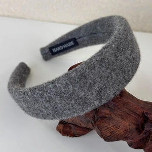Detailed shot of grey wool headband with handmade label on natural wood texture