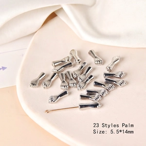 Detailed view of silver hand-shaped DIY beads, 5.5x14mm, on a ceramic display