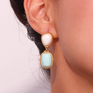 Close-up of vintage earrings featuring white drop and light blue rectangular stones