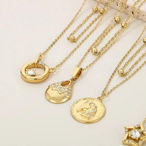 Detailed shot of layered 18K gold-plated star and unicorn pendant necklaces on stone