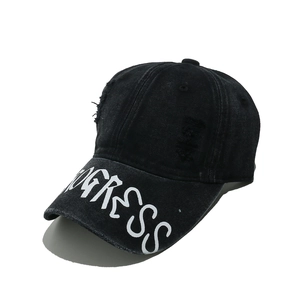 Detail of distressed black denim baseball cap with white PROGRESS print on the brim