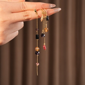 Detailed close-up of handmade glass tassel earrings with colorful beads and golden chains