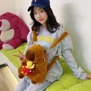 Brown capybara plush backpack featuring a red fries accessory on a model in a cozy room