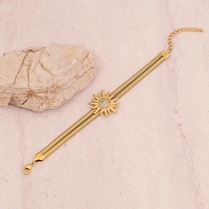 Double-layered gold flower bracelet with sun pendant on pink marble surface