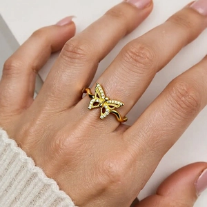 Detail of 18K gold butterfly ring with pave zircons and wavy band on a hand