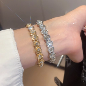 Macro detail of gold and silver geometric oval link bracelets with sparkling zircon pavé