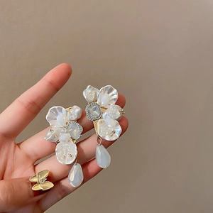Macro detail of floral pearl earrings with crystal droplets and soft pastel blue accents