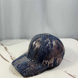 Blue washed denim baseball cap with copper sequins on white marble display stand