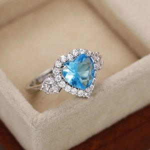 Macro shot of silver ring featuring heart-cut blue topaz and sparkling halo diamonds