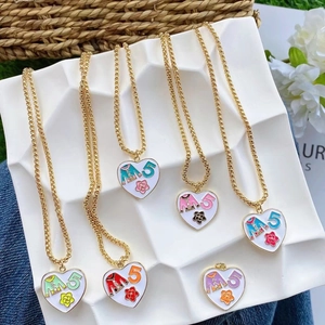 Close-up of golden necklaces with white heart pendants and number five flower motifs