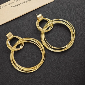 Multi-layered gold geometric hoop earrings with polished finish on black leather surface