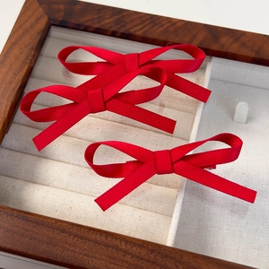Gros plan d'une paire de barrettes à nœuds en velours rouge dans un coffret à bijoux